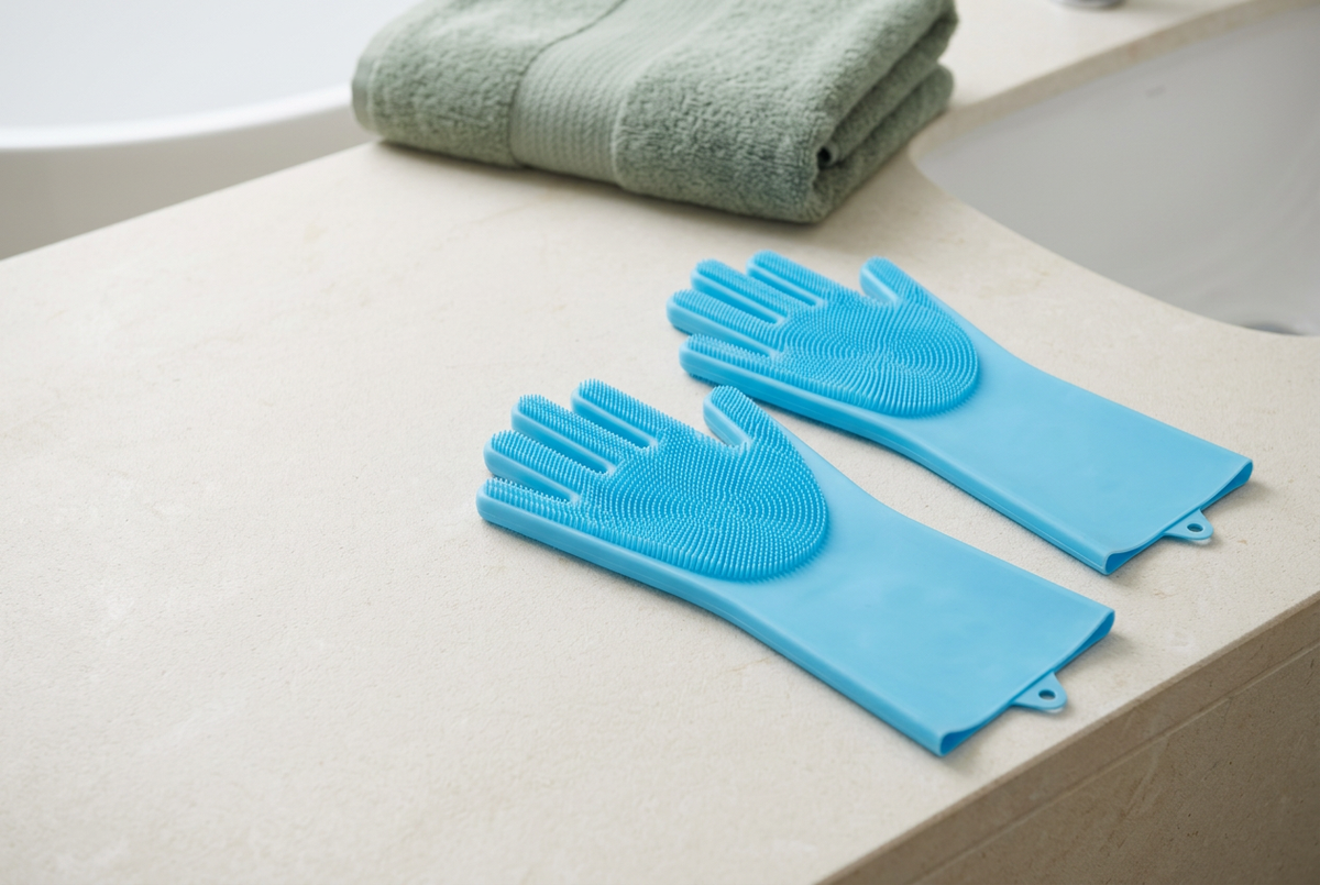 Wide composition of blue grooming gloves beside a sage towel